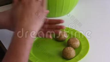 一个女人手里拿着炼乳卷着一团块饼干。 准备好的球在盘子里。 做蛋糕的基本食物。