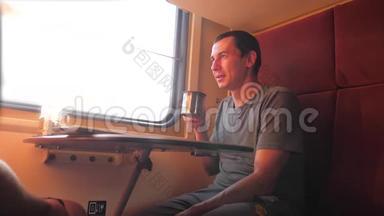 男人坐在<strong>火车车厢</strong>里，手里拿着铁路，喝着咖啡和茶。 慢动作视频。 生活方式2