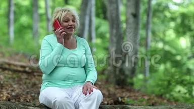 女人坐在森林中倒下的树上，通过智能手机交流