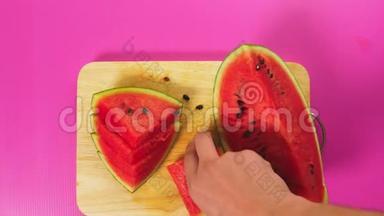 俯视图，女手用刀在木板上切水果，红色西瓜.. 天然健康食品的概念..