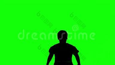 一个男人在绿色屏幕上举起双臂跳跃的剪影