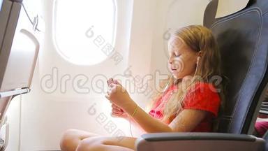 可爱的<strong>小女孩</strong>乘飞机旅行。 <strong>小</strong>孩坐在飞机窗前<strong>听音乐</strong>