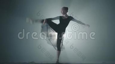 职业芭蕾舞演员在她的尖角芭蕾舞鞋上跳舞，在演播室的黑色背景上聚光灯下。 芭蕾舞演员