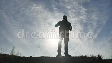 <strong>剪影</strong>阳光游客徒步旅行者背着背包从山顶欣赏日落景色。 徒步旅行者的<strong>剪影</strong>