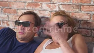 关上门。 一对年轻夫妇戴着3D眼镜，坐在客厅的沙发上，带着许多情绪，看电影。 4k