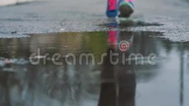 穿运动鞋的跑步者的腿的特写镜头。 女运动员<strong>在</strong>公园里慢跑，<strong>踩在</strong>泥泞的<strong>水</strong>坑里。