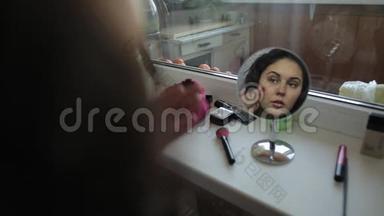 美丽的女人正在化妆看镜子
