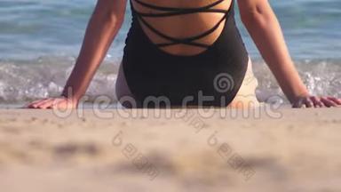 穿着黑色泳衣在白色沙滩上的女孩。 美丽的模特在海边沐浴阳光