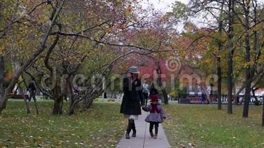 一个年轻的女人和她的女儿在公园里<strong>走来走</strong>去，在小巷里玩耍和奔跑