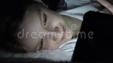 儿童在黑暗中玩平板电脑，女孩在床上浏览互联网，<strong>而不是</strong>睡觉