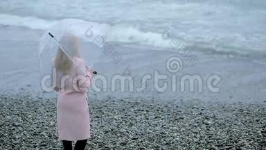 暴风雨中穿着粉<strong>红色</strong>外套，带着透明雨伞的女孩在<strong>海边</strong>。