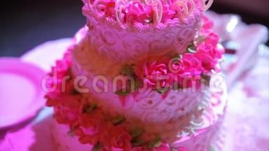 一个多层次的白色婚礼蛋糕在一个银色的底座和粉红色的花在上面。