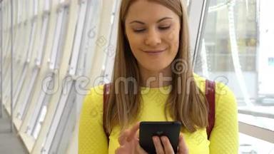 年轻漂亮的女人在<strong>商场</strong>里带着智能手机。 浏览互联网，与朋友交流。