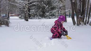 一个穿着粉<strong>红色冬季</strong>连衣裙的小女孩玩雪。