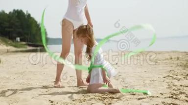 母亲和女儿穿着白色泳衣，在沙滩上用体<strong>操</strong>丝带<strong>跳</strong>舞。 夏天，黎明