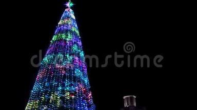 在大雪纷飞的冬夜，大圣诞树上装饰着发光的花环。 相机飞来飞去