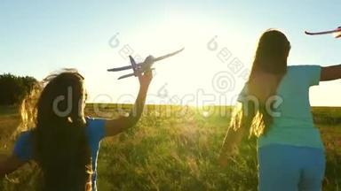 快乐的童年概念。 飞行的梦想。 两个女孩在<strong>日</strong>落时玩玩具飞机。 以太阳为背景的<strong>儿童</strong>