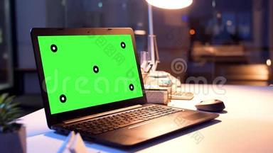夜间办公室配有绿色屏幕的笔记本电脑