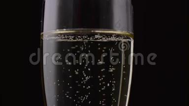 香槟倒入玻璃杯中。 黑色背景。 关门