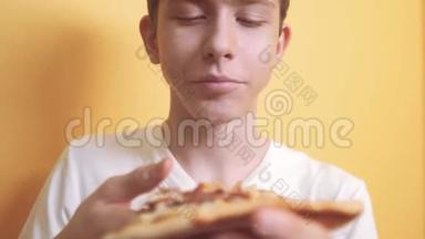 快乐的小男孩吃一片披萨的概念。 少年男孩饿了吃一片披萨。 慢视频生活方式