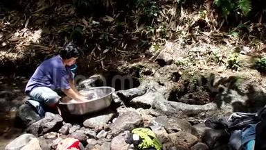 菲律宾农村<strong>社区</strong>缺乏公共供水系统<strong>设施</strong>，迫使这名妇女即使在污染的河流中也要洗衣服。
