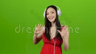 女孩通过耳机听欢快而充满活力的音乐。 绿色屏幕