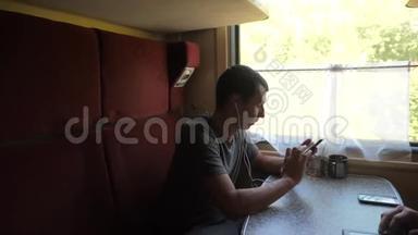 火车车厢里一个男人用耳机听音乐，用信使的生活方式写信息的剪影