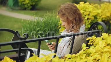 有笔记本电<strong>脑</strong>的女人在一个美丽的绿色公园的长凳上放松。 一个常年在树<strong>洞</strong>里工作的年轻女人