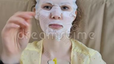 在家中的厨房里，一个正在做面膜面罩面膜的年轻女人
