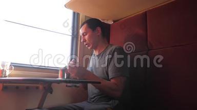 男人坐在<strong>火车车厢</strong>里，拿着智能手机，喝着咖啡和茶。 慢动作视频。 男人