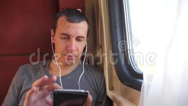 男子听音乐在火车上旅行，火车车厢车厢旅行。 慢动作视频。 一个男人