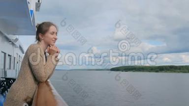 年轻女子站在<strong><strong>游</strong>轮</strong>甲板上，看着河流和风景