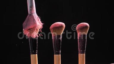化妆和美容观念.. 刷粉红色粉末爆炸黑色背景