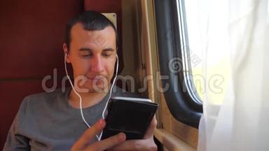男子听着火车车厢车厢车厢车厢上的音乐旅行。 慢动作视频。 有智能手机的男人
