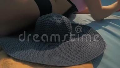 游泳池边的休息室里戴着蓝色帽子的漂亮女孩。 夏日的阳光。