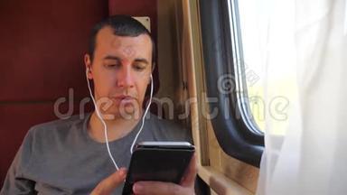 男子听着<strong>火车车厢</strong>车厢车厢车厢上的音乐旅行。 慢动作视频。 有智能手机的男人