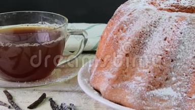 老式的沙糕，有一杯红茶和木制背景的香草片。 蛋黄海绵蛋糕