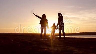 剪影，和爸爸妈妈一起快乐的孩子，日落时分的家人，夏天。 奔跑，在空中养育孩子，拥抱，爱，玩耍