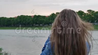 在<strong>刮风</strong>的天气里，美丽的女游客用专业的照相机在河岸上拍照
