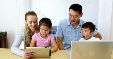 在客厅里使用数码平板电脑和笔记本电脑的幸福家庭