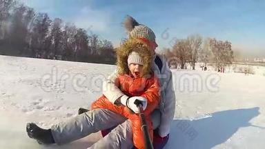 幸福的家庭乘坐和微笑的雪管在雪道上。慢动作。 冬天的雪景。 户外运动