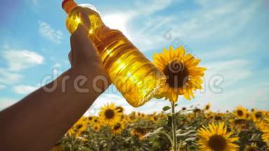农夫手里拿着一瓶塑料葵花籽油，阳光洒在他的手里。 慢动作视频。 生活方式蓝天