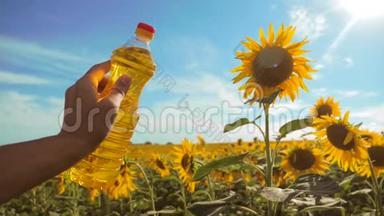 慢动作录像。 生活方式男人农民手里拿着一瓶葵花籽油在日落时的田野里。 农民农业
