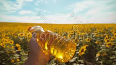 农夫手里拿着一瓶塑料<strong>葵花籽</strong>油，生活方式野外阳光。 慢动作视频。 蓝天