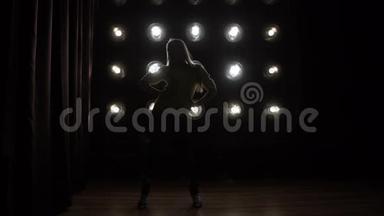 一个女孩在背景灯上跳舞的<strong>剪影</strong>。
