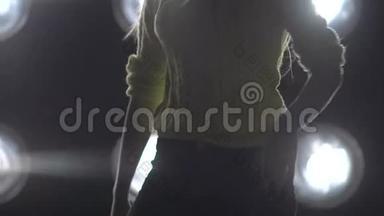 一个女孩在背景灯上跳舞的<strong>剪影</strong>。