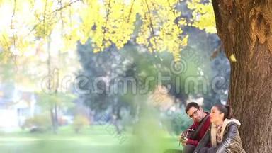 女人唱歌，男人弹吉他，坐在公园的树上