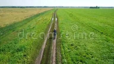 年轻人骑自行车在乡村公路上穿过绿色和黄色<strong>的田野</strong>。