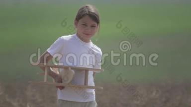 白人男孩玩模型飞机。 一个在田野里坐木飞机的孩子的肖像。