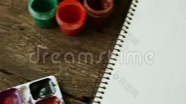 绘画套装：木制背景上的纸、画笔、颜料、水彩、丙烯酸颜料